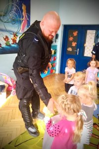 zdjęcie kolorowe - policjant w ubraniu ochronnym w trakcie wizyty w przedszkolu