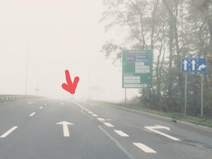 zdjęcie przedstawia drogę we mgle i ledwo widoczny samochód bez włączonych tylnych świateł