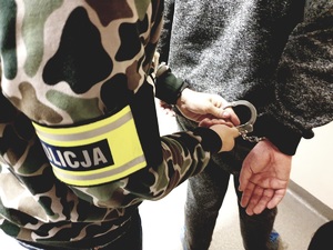 zdjęcie przedstawiające policjanta po cywilu zakładającego kajdanki zatrzymanemu - foto z archiwum policji