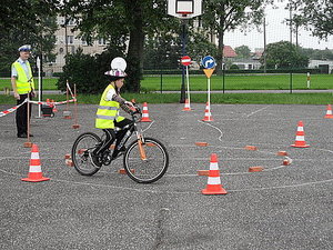 zdjęcie poglądowe przedstawiające rowerowy tor przeszkód i młodego rowerzystę jadącego pomiędzy pachołkami